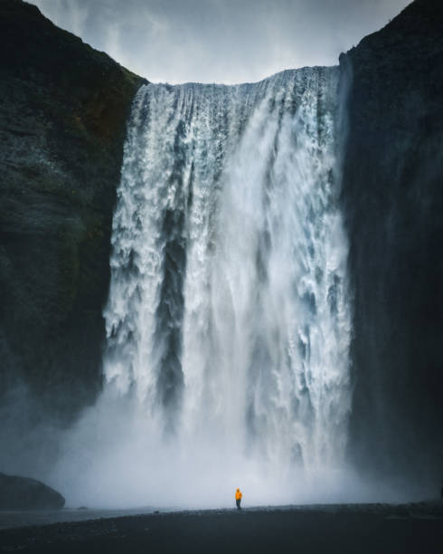 istock Hiker at gigantic Skogafoss waterfall in Iceland 985062536