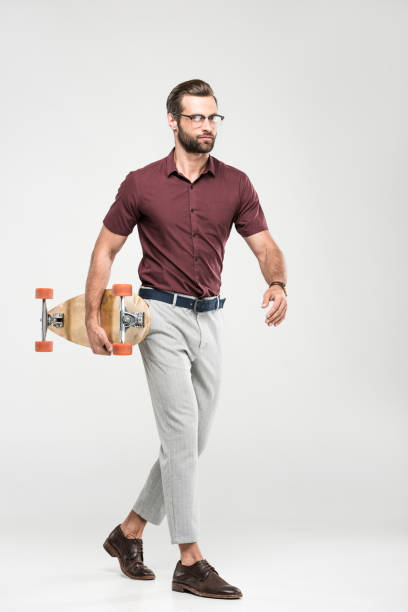 istock stylish elegant skater walking with longboard, isolated on grey 985063768
