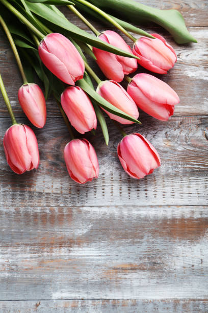 istock Pink tulips on grey wooden table 985069088