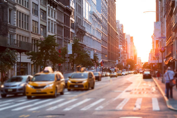 Sunlight shines down the streets of New York City with taxis stopped at the intersection stock photo