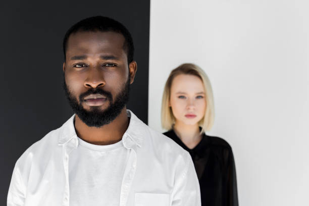 istock multicultural couple looking at camera near black and white wall, yin yang concept 985074036