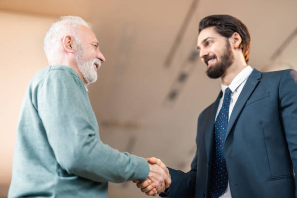 istock Happy senior man shaking hands with insurance salesman. 985074292