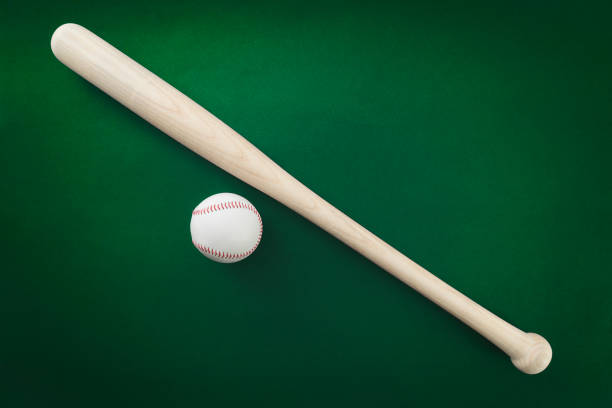 istock Baseball bat and ball on green background 985074988
