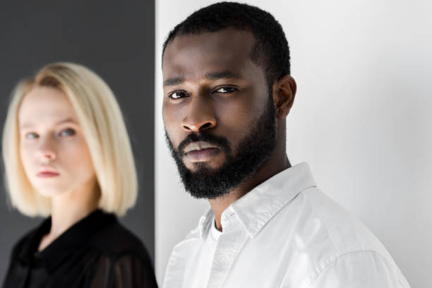 istock multicultural couple looking at camera near black and white wall 985079538