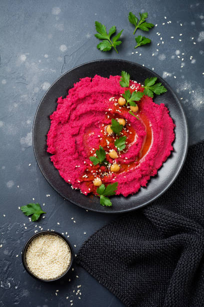 Homemade beetroot hummus in black ceramic dish on old dark concrete background. Selective focus. Top view.