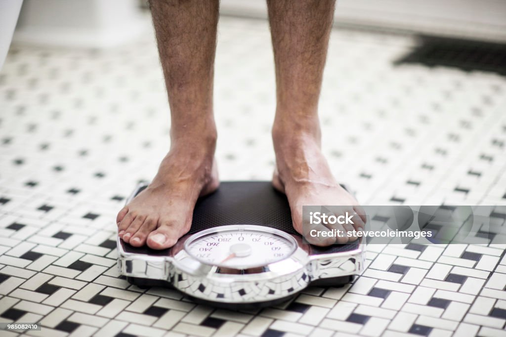 Adult man on bathroom scales. Weight Scale Stock Photo