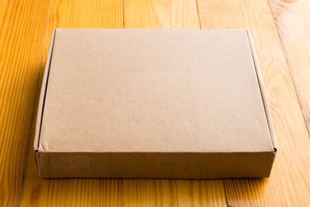 istock Craft unlabeled cardboard box with copyspace for text on wooden 985088382
