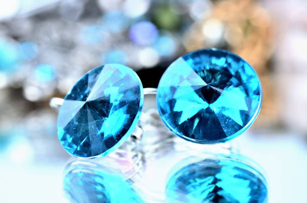 istock Close-up of blue earrings jewels - reflection effect - colored backgrounds 985100104