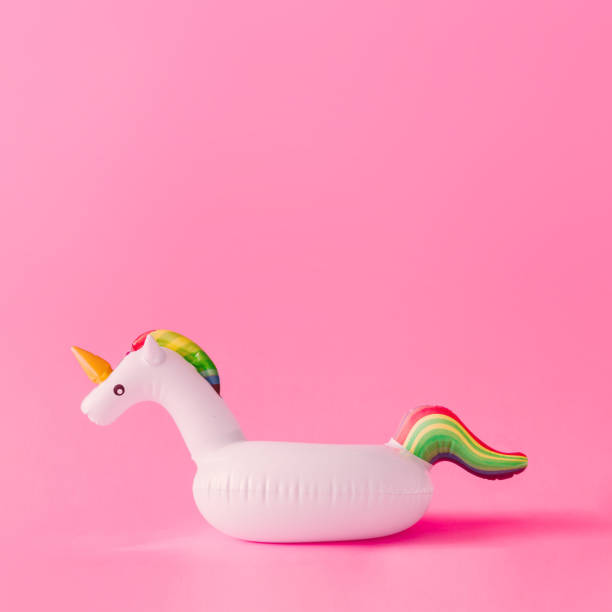 Inflatable unicorn pool toy on pastel pink background. Minimal summer concept. Inflatable unicorn pool toy on pastel pink background. Minimal summer concept. Unicorn stock pictures, royalty-free photos & images