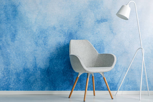 istock Chair and white lamp set on an empty, blue wall. Place your product 985113920