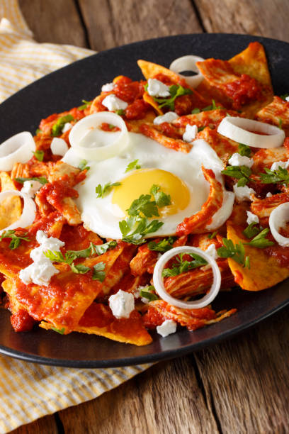 istock Mexican breakfast: chilaquiles with egg and chicken close-up. Vertical 985118514