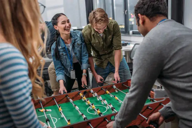 happy multicultural people playing in table soccer at modern office