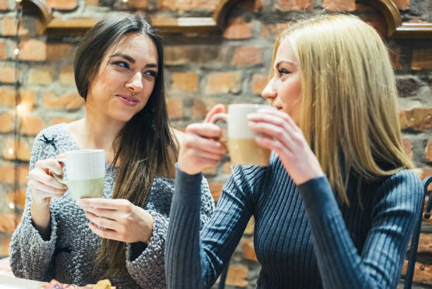 istock Two girls in cafe with hot drinks 985130162