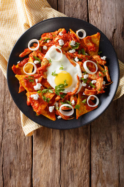 istock Mexican nachos with tomato salsa, chicken and egg close-up. Vertical top view 985132052