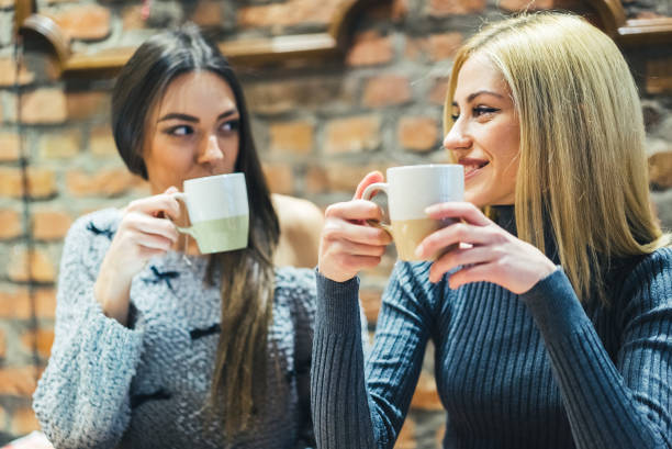 istock Two girls in cafe with hot drinks 985132440
