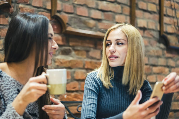 istock Two girls in cafe talking 985133574