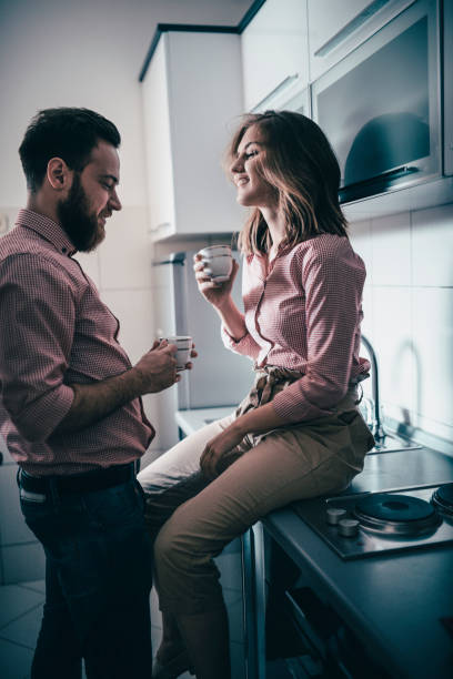 istock Husband And Wife In Same Shirts Drinking Morning Coffee In Kitchen 985147846