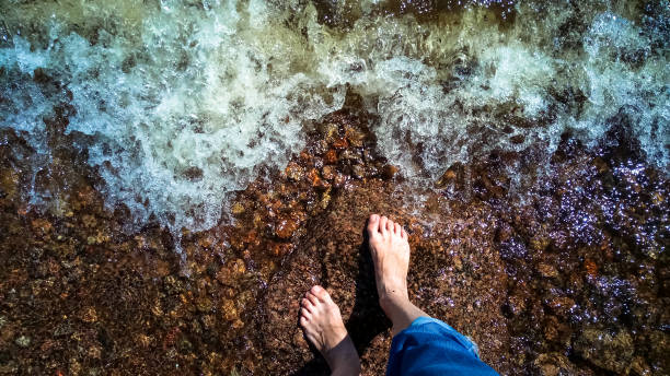 istock Feet in the dark water of an approaching wave. 985148018