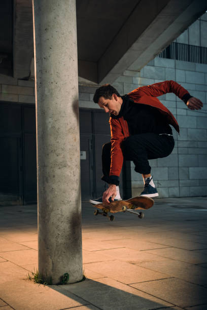 istock handsome young skateboarder performing jump trick in urban location 985151206