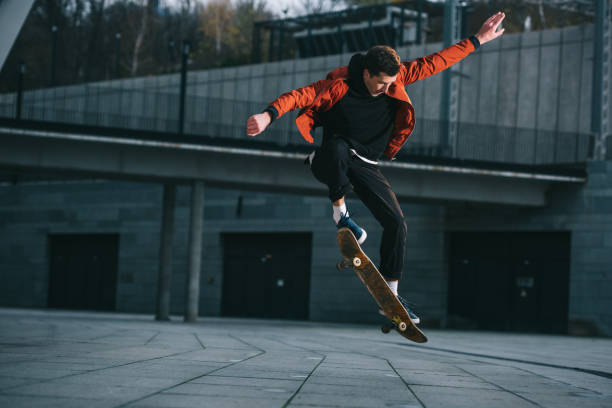 istock skateboarder doing jump trick in urban location 985158106