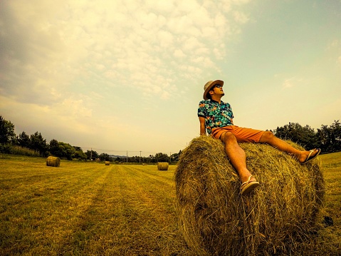 young guy is sitting on hay stack while his journey.  The place is Aomori in Japan