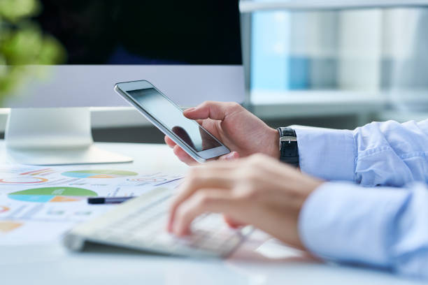 crop entrepreneur with smartphone at workplace - business blurred motion text messaging defocused imagens e fotografias de stock