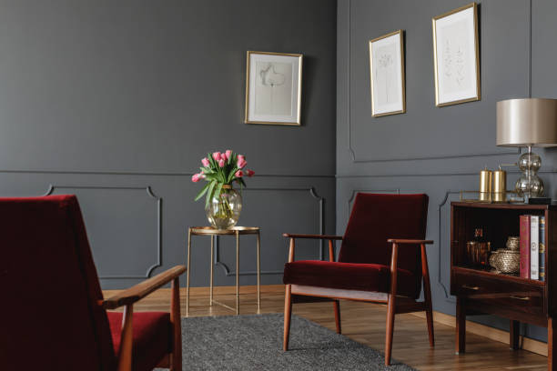 istock Elegant psychologist's office interior with two red armchairs facing each other between a golden table with flowers and vintage, wooden cabinet. Real photo 985162748