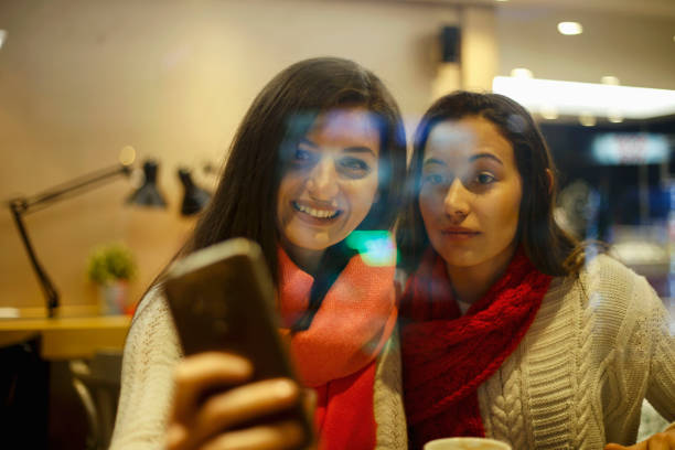 istock Two women friends sitting in cafe and make selfie. 985166510