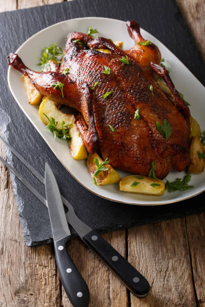 istock Delicious festive duck with apples and greens close-up on a table. vertical 985169950