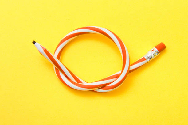 istock Flexible pencil on a yellow background. Bent pencils two-color 985174884