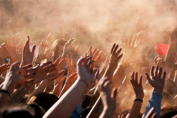 Crowded people hands up at a day time concert.