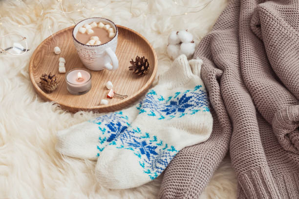 istock Socks, sweater and hot cocoa on the fur rug. 985188002