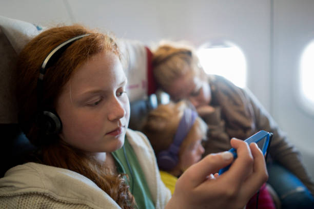 istock Girl sitting on a plane using smartphone to spend time while waiting for landing 985188434