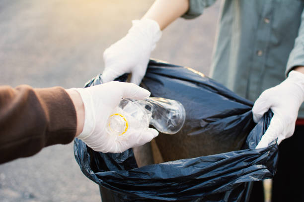 istock Cropped Hand Wearing Protective Glove While Putting Plastic Bottle In Bag 985191464