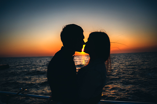 Silhouette of a couple at the beach at sunrise sky summer time, seashore summer beach at yellow blue evening horizon sea, sunset background.