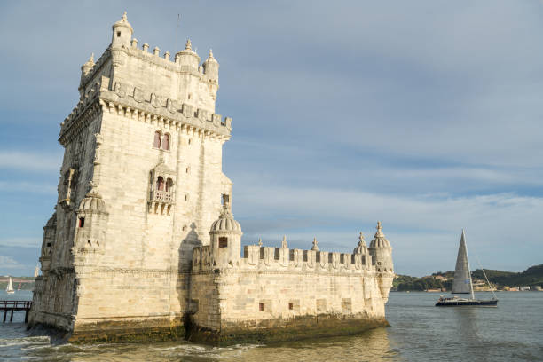 Small sailing boat passing Tower of Belem in Lisbon Lisbon, Portugal - April 21,2018: Small sailing boat passing Tower of Belem in Lisbon, Portugal during April 2018 keep fortified tower photos stock pictures, royalty-free photos & images