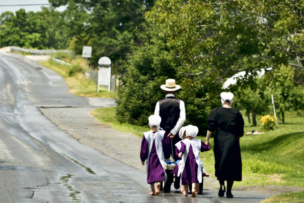 Daily life in Rural USA, Lancaster County, PA Lancaster County, PA, USA - June 24, 2018; After returning from Sunday church an Amish family walks bare feet over a country road in the heart of rural Lancaster County, Pennsylvania, on June 24, 2018. Amish stock pictures, royalty-free photos & images