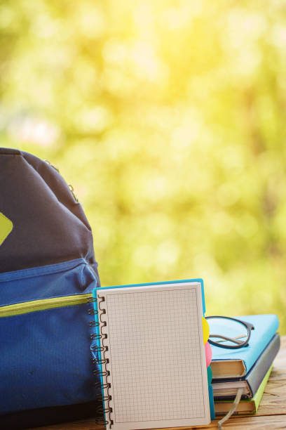 istock School backpack with books on wooden table and nature background 985232708