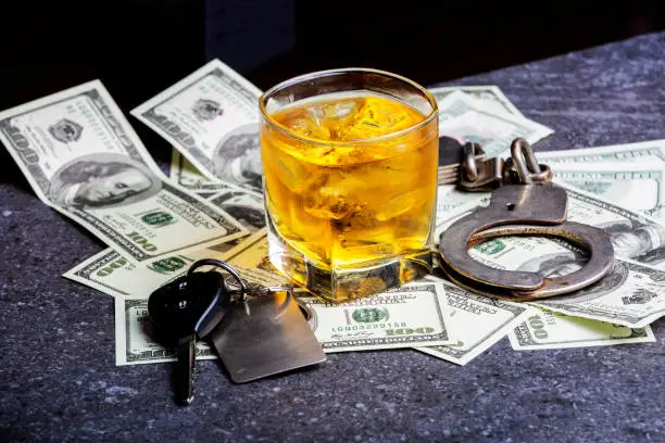 Car keys, alcohol, dollars and handcuffs to illustrate that you will go to jail if you dink and drive