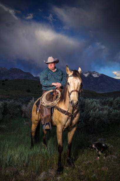 istock Cowboy with Horse and Dog Under Dramatic Sky 985246876