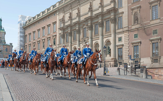 Stockholm, Sweden - June 14, 2018: Mounted Royal Guards in uniforms and silver helmets riding the horses on square of Old Town on June 14, 2018. In the capital of Sweden live 1 million people