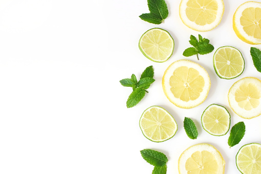 Styled stock photo. Summer herbs and fruit composition. Lime, lemon slices and fresh green mint leaves isolated on white table background. Juicy food pattern, empty space. Flat lay, top view.