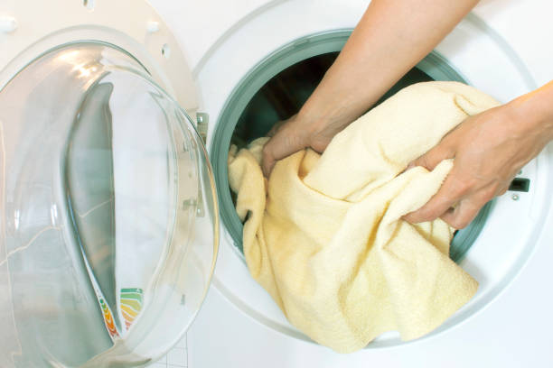 istock Womans hands pull the laundry out of or load the washing machine 985272922