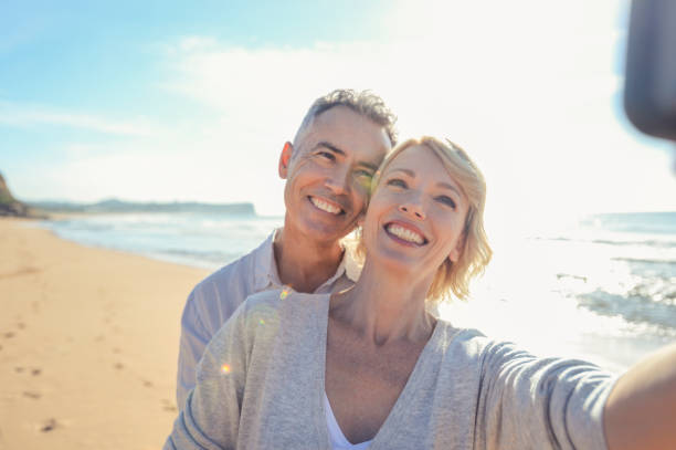 성숙한 부부 휴대 전화와 함께 해변에 있는 selfie를 복용 - australia photographing camera beach 뉴스 사진 이미지