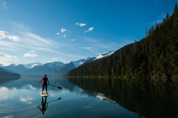 Woman paddling on a stunning mountain lake stock photo