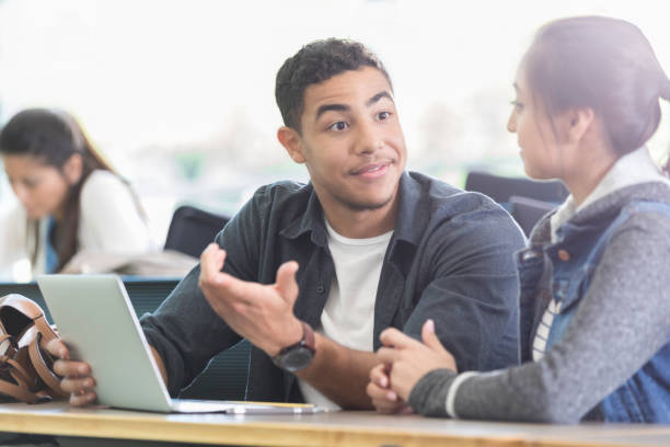 istock Handsome male college student talking with classmate 985296126