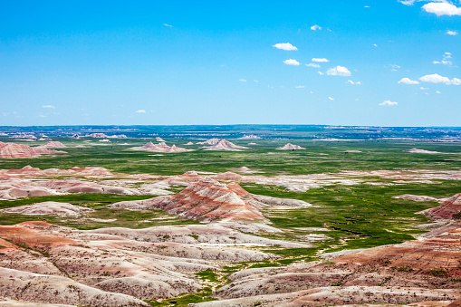 Multi-colored rock formations and mountains rising over the plains of Badlands National Park.