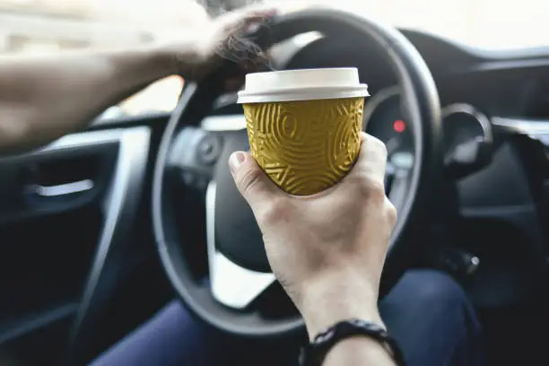 Photo of Male hold coffee and drive the car