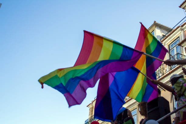 istock People waving LGBT rainbow flags at an gay pride parade 985331148