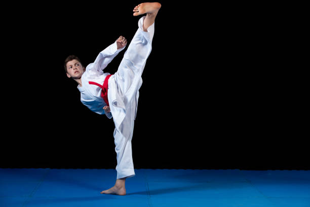 istock Young boy dressed in a white karate kimono with red belt. 985355156